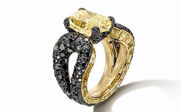 一颗5.77ct的枕形切割黄钻，点缀21颗长阶梯形切割黄钻和401颗圆形切割黑钻的金戒指