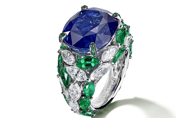 主石为一颗16.89ct的椭圆形切割蓝宝石，点缀21颗榄尖形祖母绿，17颗榄尖形钻石，55颗圆形祖母绿，15颗蓝宝石的白金戒指